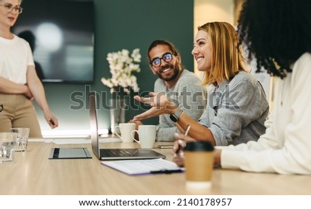 Cheerful businesswoman having a discussion with her colleagues in a boardroom. Group of happy businesspeople sharing ideas during a meeting in a modern workplace. Royalty-Free Stock Photo #2140178957