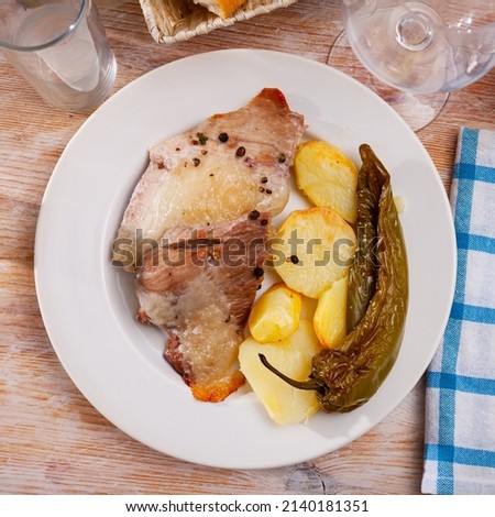 Close up of tasty baked pork with potatoes and baked green pepper, served on plate
