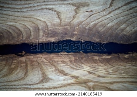 The desk is covered with epoxy resin and varnished. Luxury quality wood processing. A black epoxy river in a round tree slab. Wooden background, pattern, texture. Space for text. High quality photo
