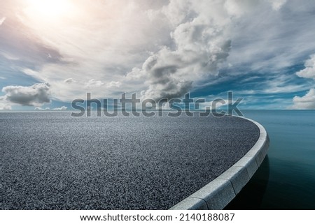 Round asphalt road platform near the lake under blue sky Royalty-Free Stock Photo #2140188087