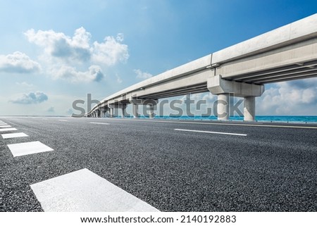 Empty asphalt road and river with bridge under blue sky Royalty-Free Stock Photo #2140192883