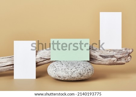 White and green paper business card mockup. Natural stone and driftwood on beige background