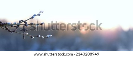 christianity cross and willow branches against blurred sunny natural background. Easter holiday, Orthodox palm Sunday. Symbol of Christianity, Lent, Faith in God, Church holiday. banner. copy space