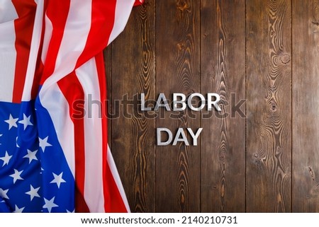 words labor day laid with silver metal letters on wooden surface with crumpled USA flag on left side in directly above high angle view