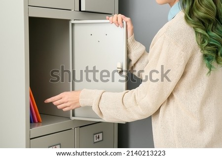 Beautiful female student opening her locker at the university Royalty-Free Stock Photo #2140213223