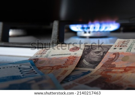 Russian currency on the background of the dollar and burning gas.The concept of gas and oil payment in Russian currency.Selective focus. Royalty-Free Stock Photo #2140217463