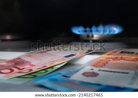 Euro banknotes against the background of Russian banknotes and a gas burner. Gas crisis concept.Cash. High prices for natural resources. Tongues of flame. Public debt.Selective foсus