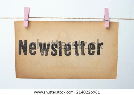 Newsletter written on yellowed vintage paper and hanged on a jute rope with pink clips 