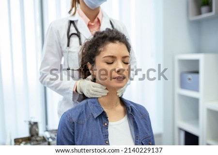 Endocrinologist examining throat of young woman in clinic. Women with thyroid gland test . Endocrinology, hormones and treatment. Inflammation of the sore throat Royalty-Free Stock Photo #2140229137
