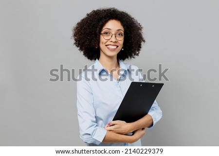 Young confident employee business corporate lawyer woman of African American ethnicity in classic formal shirt work in office clipboard with papers document isolated on grey color background studio Royalty-Free Stock Photo #2140229379