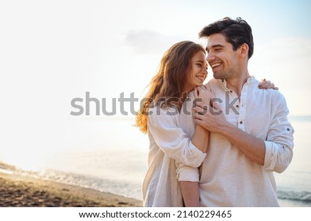 Smiling young couple two friends family man woman 20s in casual clothes hug girlfriend put head on boyfriend shoulder at sunrise over sea sand beach ocean outdoor seaside in summer day sunset evening