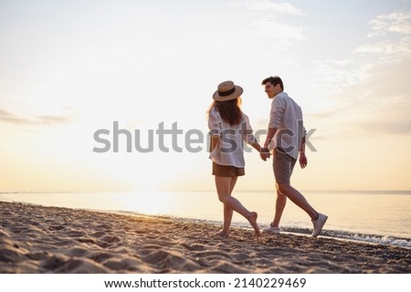 Full body back view young lovely couple two friends family man woman in casual clothes hold hands walking stroll together at sunrise over sea beach ocean outdoor exotic seaside in summer day evening Royalty-Free Stock Photo #2140229469