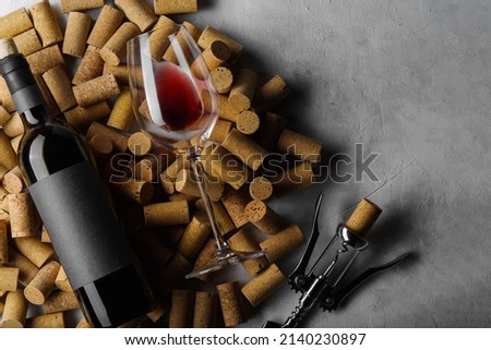 original composition. A bottle of wine, a wine glass and a corkscrew lie on wine corks. Isolated on a gray background. There is free space to insert. Holiday, romantic evening, date.