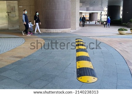 Yellow and Black Striped Speed Bump in residential area in family and pedestrian and granite pavement Background, Mid-Day
