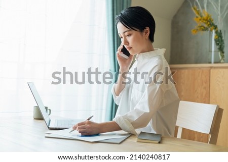 Woman making a phone call while working remotely Royalty-Free Stock Photo #2140240817