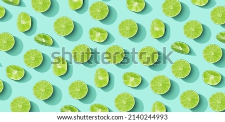 Lime fruit as bring summer food pattern, slices of green citrus with hard shadows at sunlight on pastel mint background. Healthy fruits food concept. Monochrome flat lay with juicy lime, wide banner