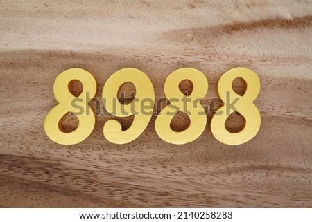 Wooden  numerals 8988 painted in gold on a dark brown and white patterned plank background.