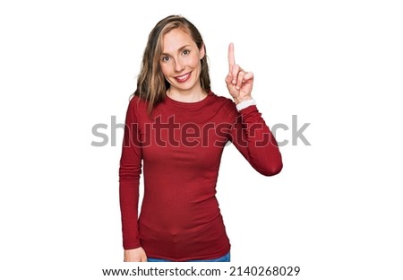 Young blonde woman wearing casual clothes pointing finger up with successful idea. exited and happy. number one. 