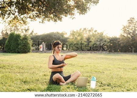 Qigong chinese meditation online with laptop in green park. Sport training outdoor. Fit asian girl is meditating outside Royalty-Free Stock Photo #2140272065