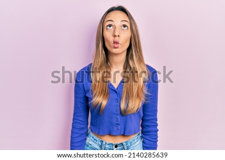 Beautiful hispanic woman wearing casual blue shirt making fish face with lips, crazy and comical gesture. funny expression. 
