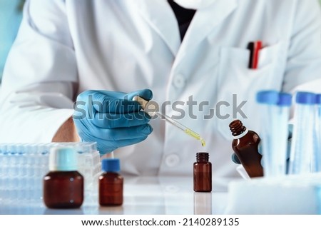 researcher dosing and mixing fluid liquids in the chemistry lab. hands of chemist pipetting in a bottle drop of yellow fluid perfume in the product research laboratory Royalty-Free Stock Photo #2140289135