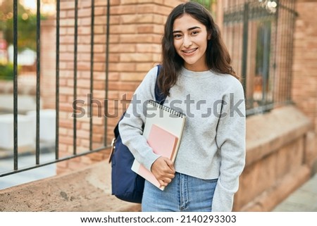 Young middle east student girl smiling happy holding book at the city. Royalty-Free Stock Photo #2140293303
