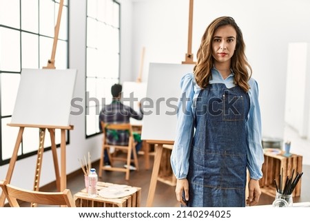 Young artist woman at art studio relaxed with serious expression on face. simple and natural looking at the camera. 