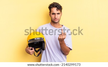 hispanic handsome man feeling angry, annoyed, rebellious and aggressive. motorbike helmet concept