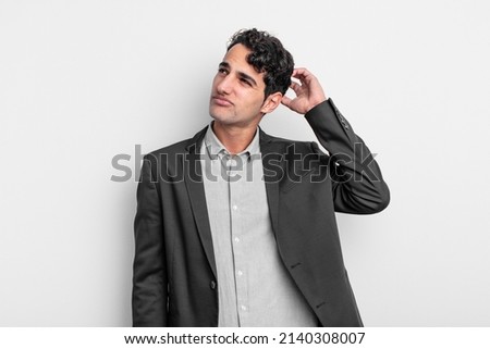 young businessman feeling puzzled and confused, scratching head and looking to the side