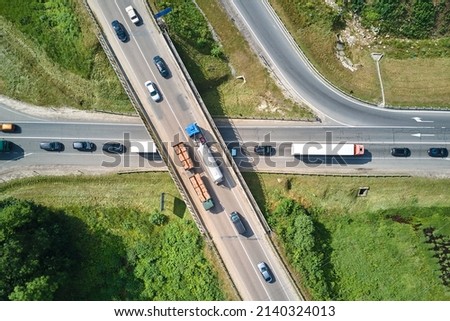 Aerial view of road intersection with fast moving heavy traffic on city streets. Uban transportation during rush hour with many cars and trucks Royalty-Free Stock Photo #2140324013