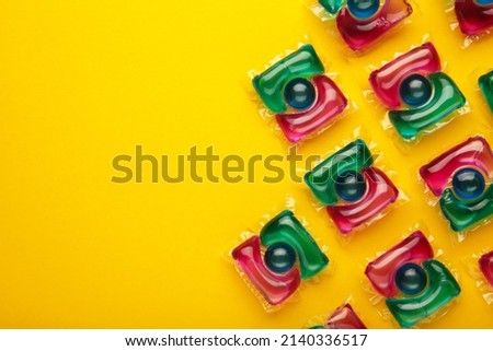 Washing powder in capsules on a yellow background. Top view.