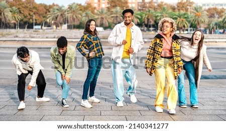 Multiracial students walking at Barceloneta beach broadwalk doing funny move - Trendy guys and girls having fun together on party mood - Travel life style concept on bright filter - Focus on mid frame Royalty-Free Stock Photo #2140341277