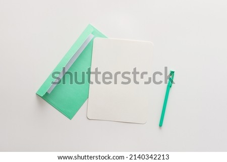 Green mint envelope with blank paper and pen, greeting card or invitation mockup, top view, copy space