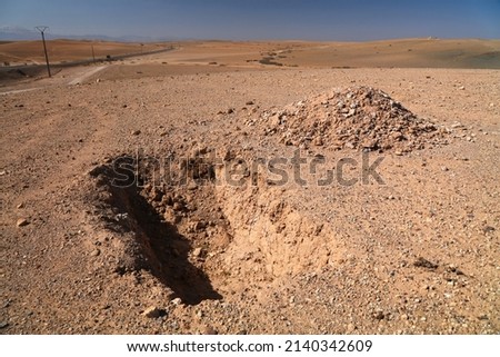 Shallow grave in the desert. Agafay desert near Marrakesh, Morocco. Royalty-Free Stock Photo #2140342609