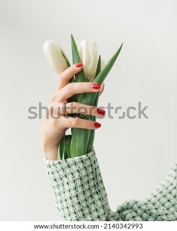 bouquet of white tulips in the hand of a girl in a tweed green suit, close-up view. girl holding flowers. spring concept, fresh spring colors