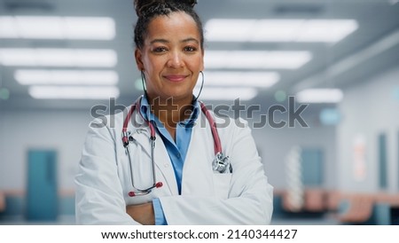 Medical Hospital Medium Portrait: African American Female Medical Doctor Takes of Glasses Looks Sincerely at Camera and Smiles. Successful Health Care Physician in White Lab Coat Ready to Save Lives Royalty-Free Stock Photo #2140344427