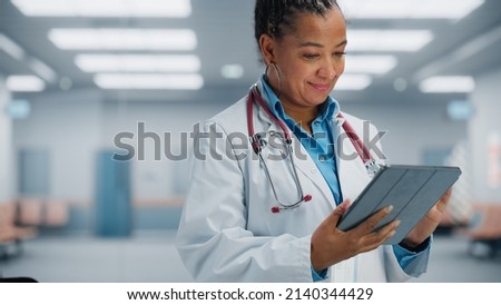 Medical Hospital Portrait: Confident African American Female Medical Doctor Using Digital Tablet Computer. Health Care Black Physician in White Lab Coat Prescribes Medicine, Ready to Save Lives Royalty-Free Stock Photo #2140344429