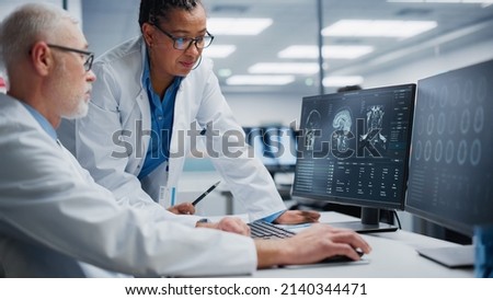 Medical Hospital: Happy Neurologist and Neurosurgeon Talk, Use Computer, Analyse Patient MRI Scan, Diagnose Brain. Brain Health Research Clinic: Two Smiling Physicians Look at CT Scan find Treatment Royalty-Free Stock Photo #2140344471