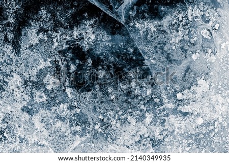 Ice texture background. The textured cold frosty surface of the ice with cracks on the dark blue background. Royalty-Free Stock Photo #2140349935