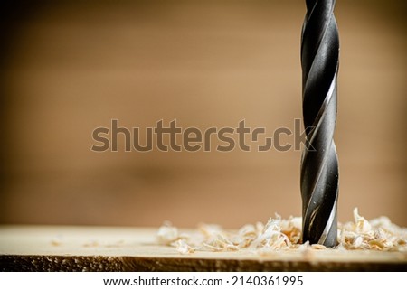 Piece of wood is drilled with shavings. On a wooden background. High quality photo