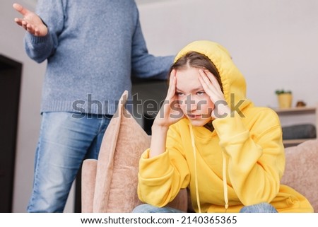 Dad swears at her daughter at home. Conflict between man and child. Father screams at the sad teen girl Royalty-Free Stock Photo #2140365365