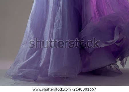 Close-up of a blue chiffon dress curiously bending on girl in the studio. Lavender fabric tulle texture. Pantone color of the year 2022 very peri.