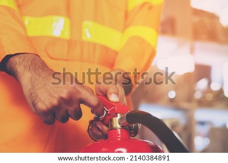 Fireman hand holding fire extinguisher. available in emergencies conflagration damage background. Safety concept.