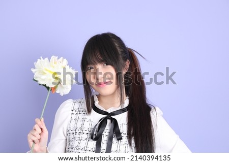 The young Asian girl in white preppy dressed standing on the purple background.