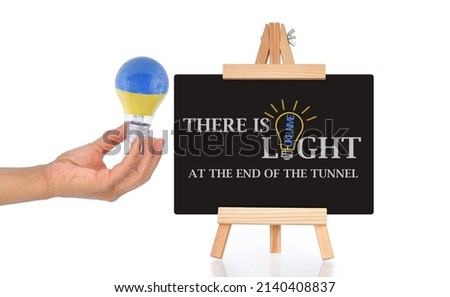 There Is light At the End of the Tunnel Blackboard and hand holding light bulb on white background
