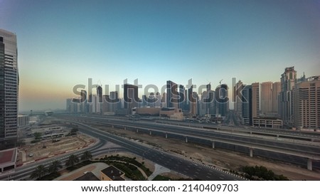 Dubai Marina skyscrapers and Sheikh Zayed road with metro railway aerial panoramic timelapse during all day. Traffic on a highway near modern towers with shadows moving fast, United Arab Emirates