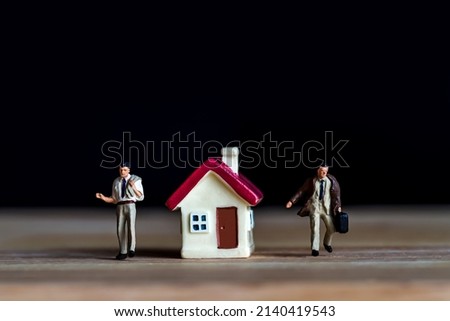 miniature people standing with tiny home on wooden floor over dark  background