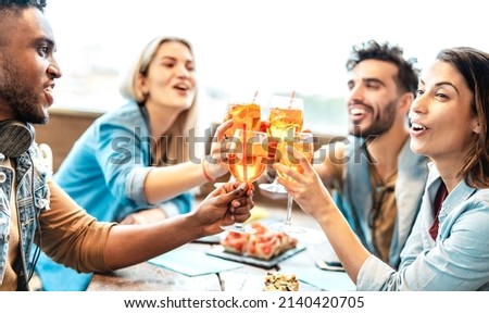 Friends toasting spritz at cocktail bar restaurant - Trendy life style concept with young people having fun together toasting fancy drinks on happy hour time - Backlight filter with focus on glasses