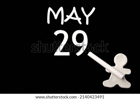29th day of May. A small white plasticine man writing the date 29 May on a black board. Business concept. Education concept. Spring month, day of the year concept.