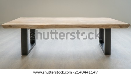 A coffee table made of exotic Suar wood. The table top is attached to massive metal legs. The table is in an industrial style. Royalty-Free Stock Photo #2140441149